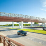 Cars drive under the 183 Toll pedestrian bridge