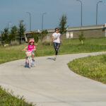 Woman running and little girl biking on 290 Trail
